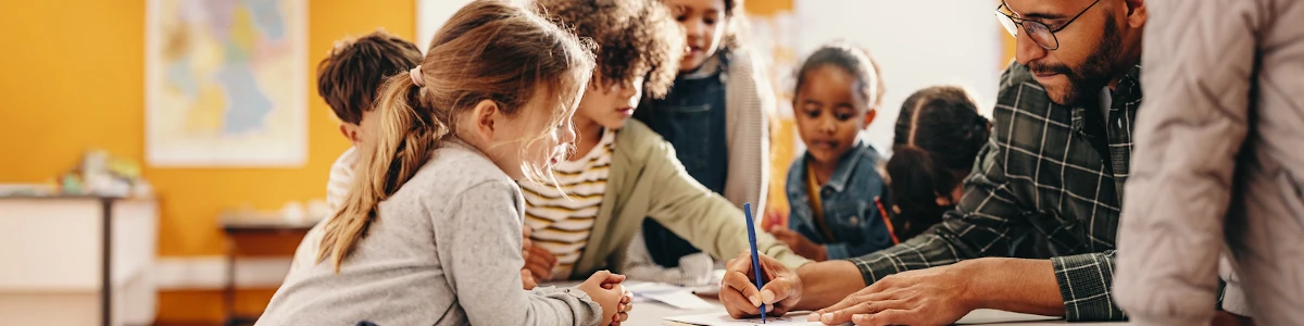 Teacher working with young students at a table